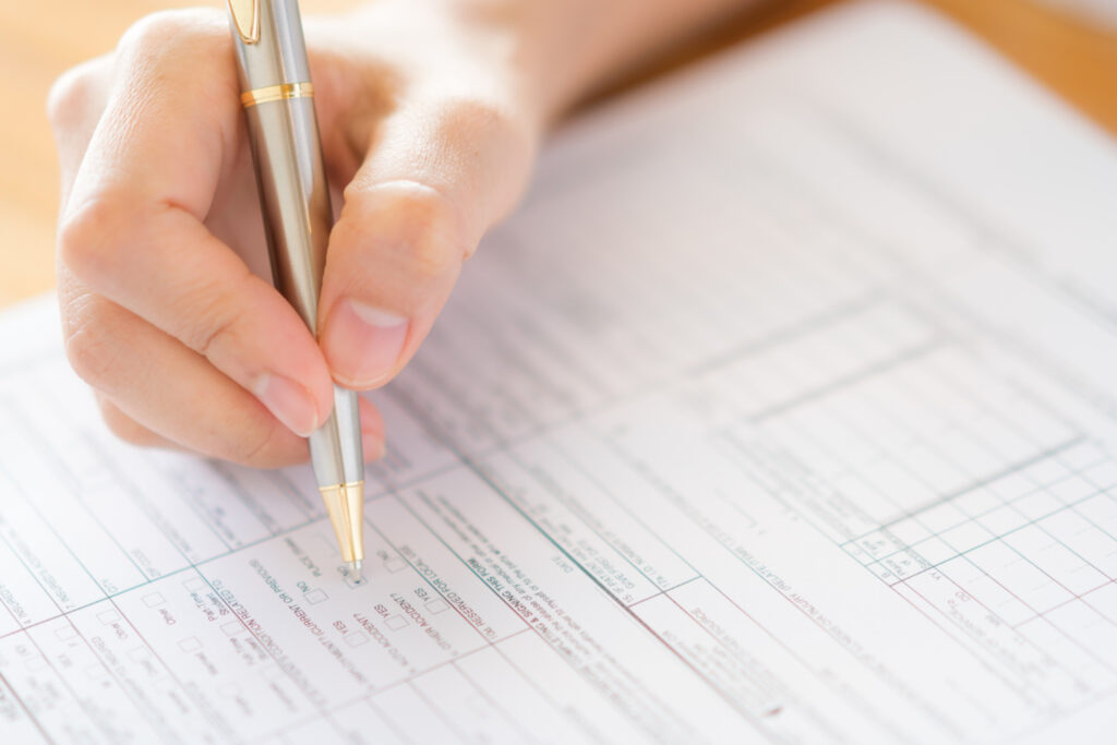 an image of a hand holding a pen filling out checkboxes on a page, simulating what it might be like if they didn't use a certn background check.